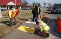 Three men working on a sidewalk project.