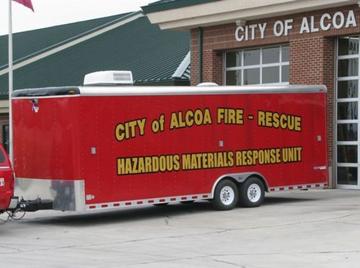 A large red trailer with words on the side, "City of Alcoa Fire-Rescue, Hazardous Materials Respo
