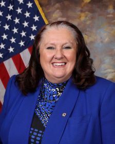 Commissioner Tracey Cooper professional headshot with American Flag background