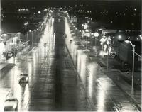 A black and white photo of a lighted freeway at night.