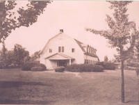 A black and white photo of a white barn house.