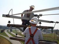 Two workers high on an electric pole performing maintenance.