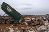 A dump truck dumping its load onto a pile.
