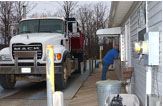 A large white truck parked next to a white building.