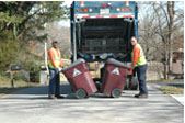 Two workers loading trash onto a truck.