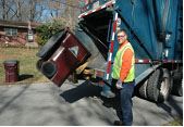 A worker loading trash onto a truck.