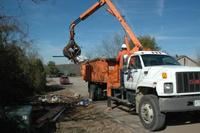 A large white truck collecting waste from the side of the road.